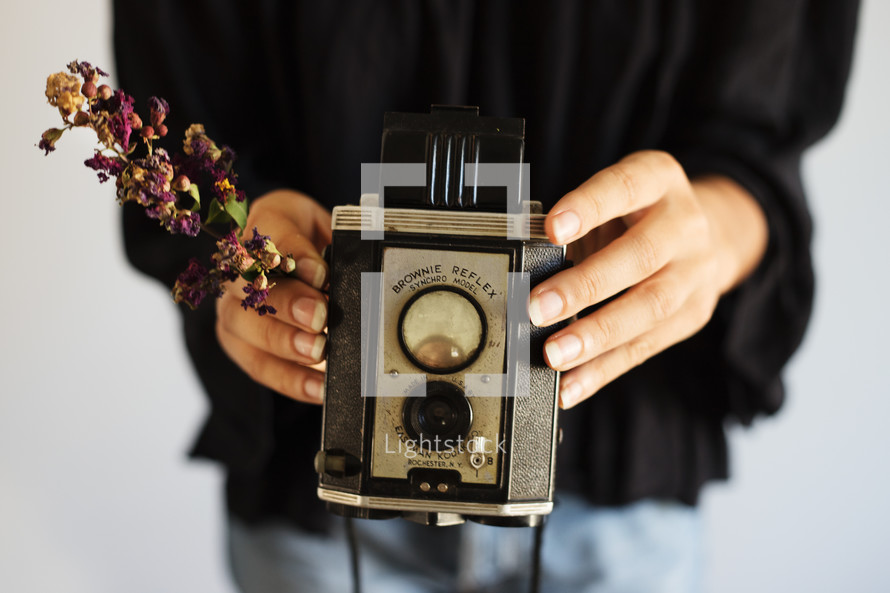woman holding a box camera and flowers