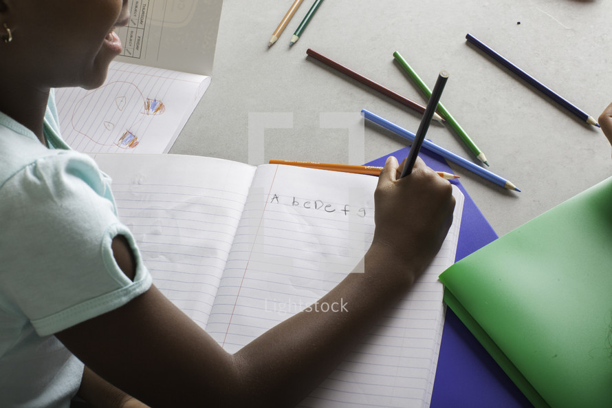 a girl writing her ABC's 