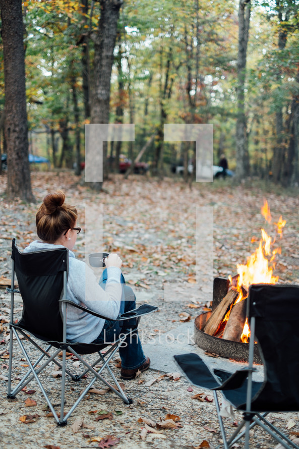 woman sitting near a campfire 