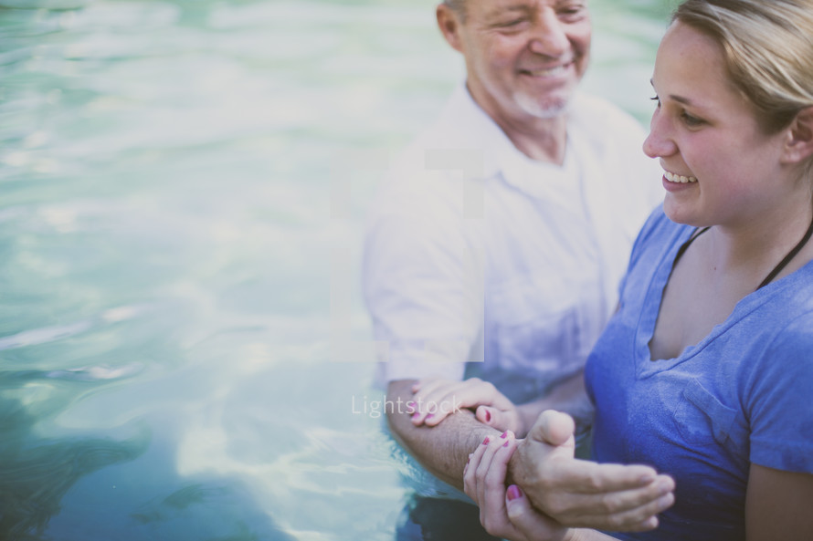 Man baptizing a woman in a pool of water.
