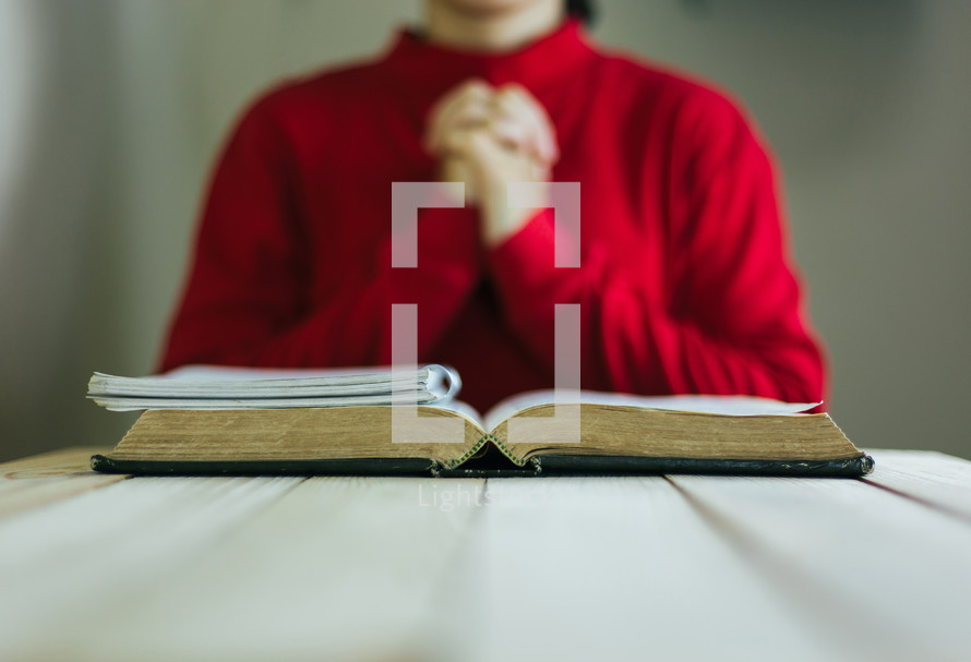 a person praying in front of a Bible 