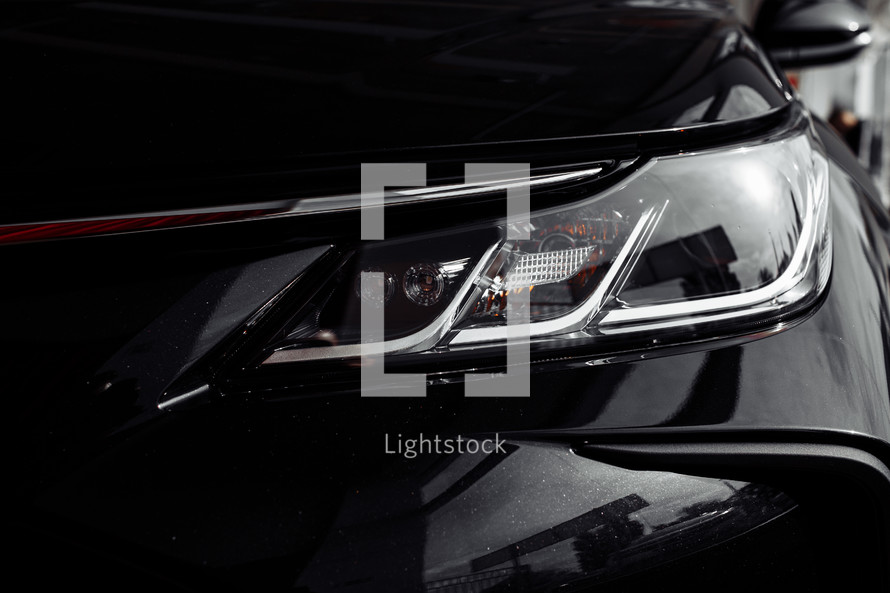 headlight of modern prestigious black car close up. Close up photo of modern car, detail of headlight. Headlight car Projector LED of a modern luxury technology and auto detail. selective focus.