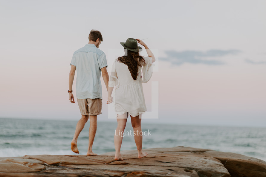 a couple walking on a beach holding hands 