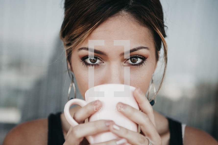 a woman looking up while sipping coffee 