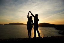 a man and woman dancing at sunset 