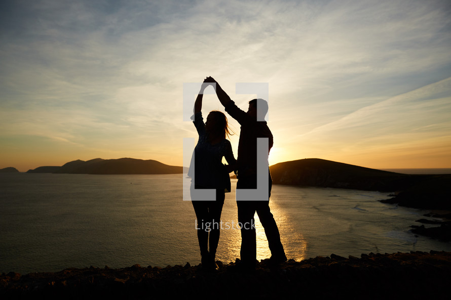 a man and woman dancing at sunset 