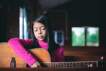 a girl child playing a guitar 
