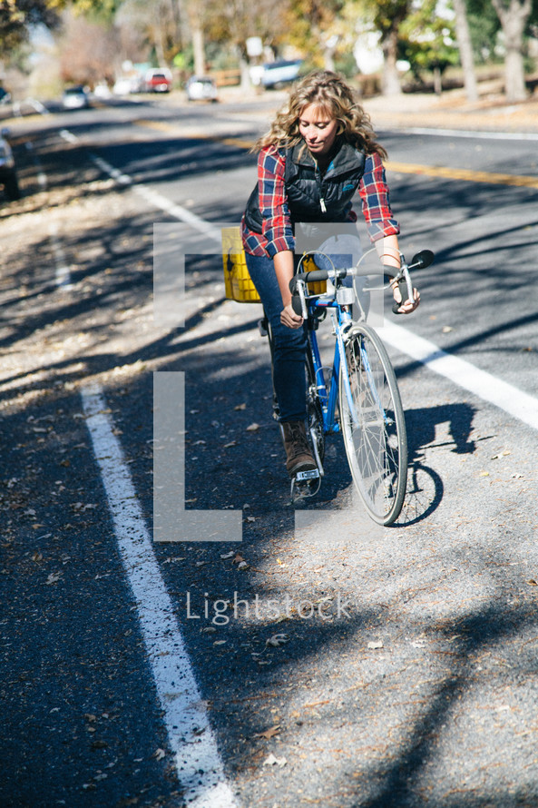 a woman riding a bicycle down a neighborhood street 