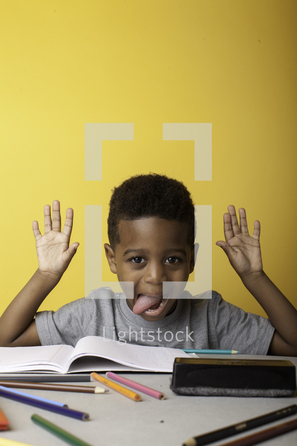 a boy child sticking out his tongue at a table 