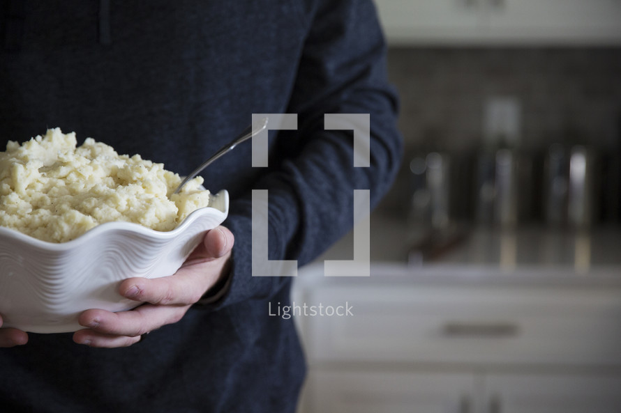 a man holding a bowl of mashed potatoes 