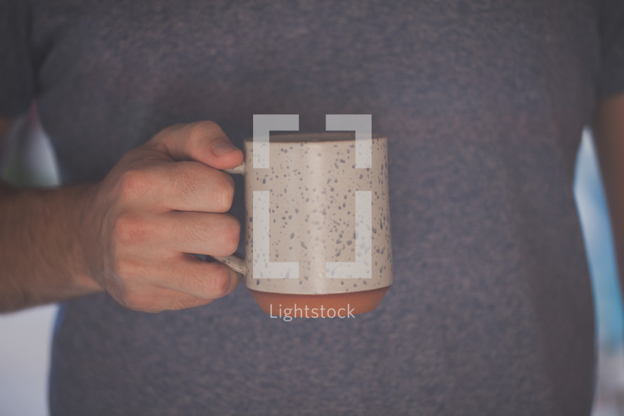 A hand holding a white coffee mug