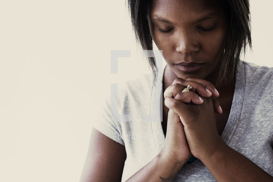 African-American woman with head bowed in prayer 