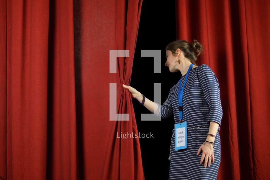 a woman checking behind the curtains on stage, back stage pass