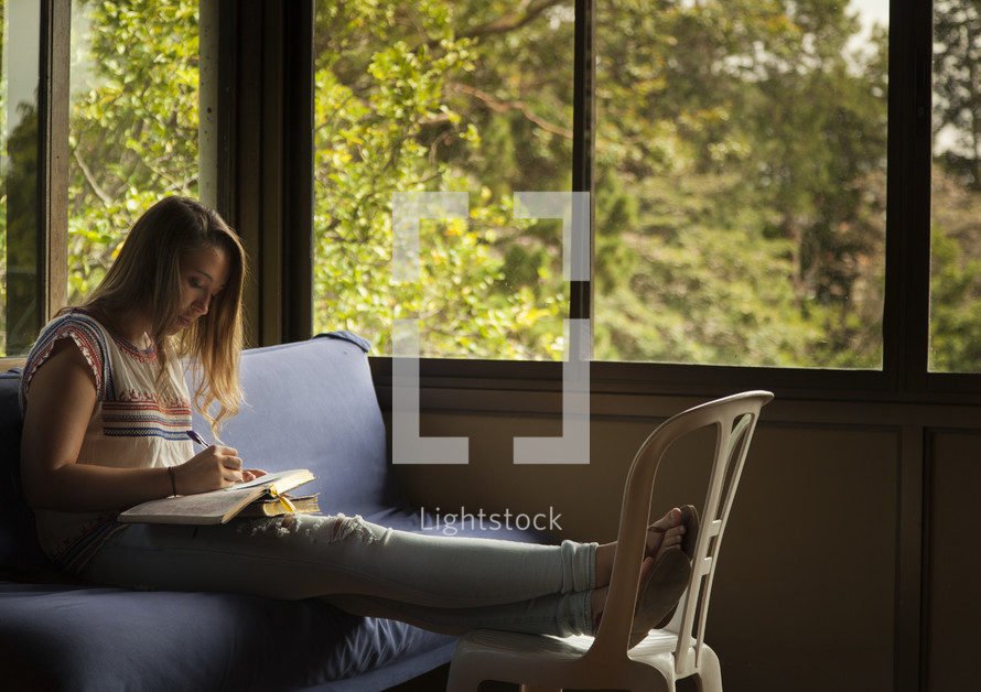 girl reading a Bible on a couch 