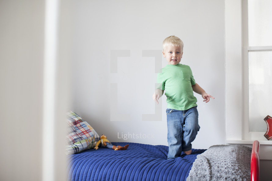 toddler boy jumping on his bed.