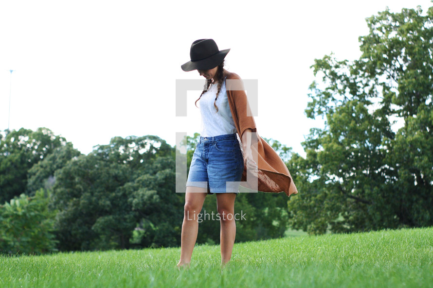 a woman walking through a field of grass