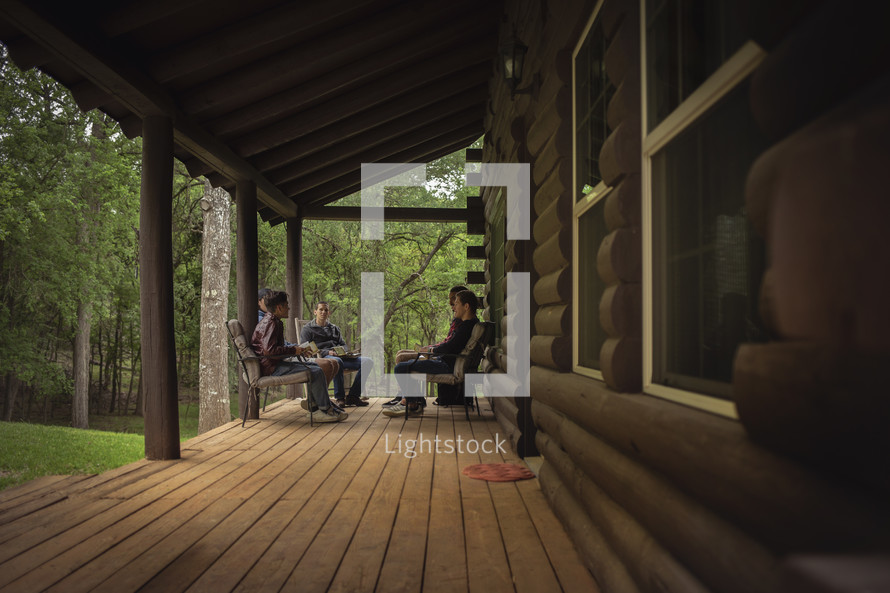 teen boys sitting on a cabin porch discussing scripture 