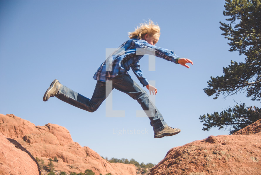 boy child leaping across rocks 