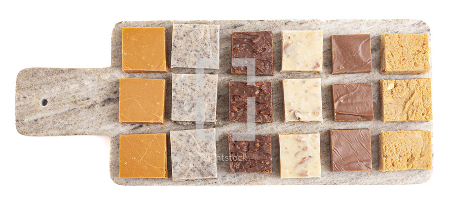 Chocolate fudge dessert squares on stone board on white background