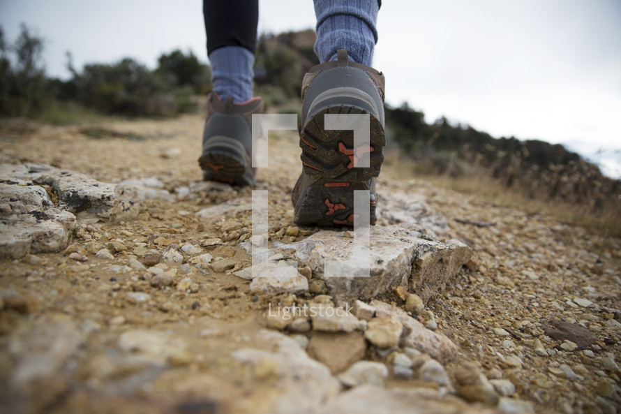 close up of person's boots hiking up a mountain.
