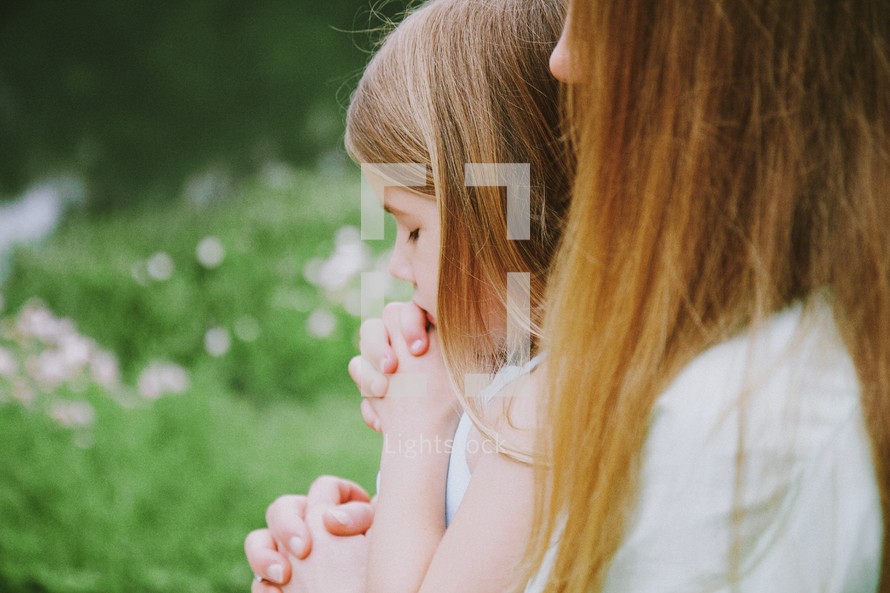 Mother and daughter praying outside.