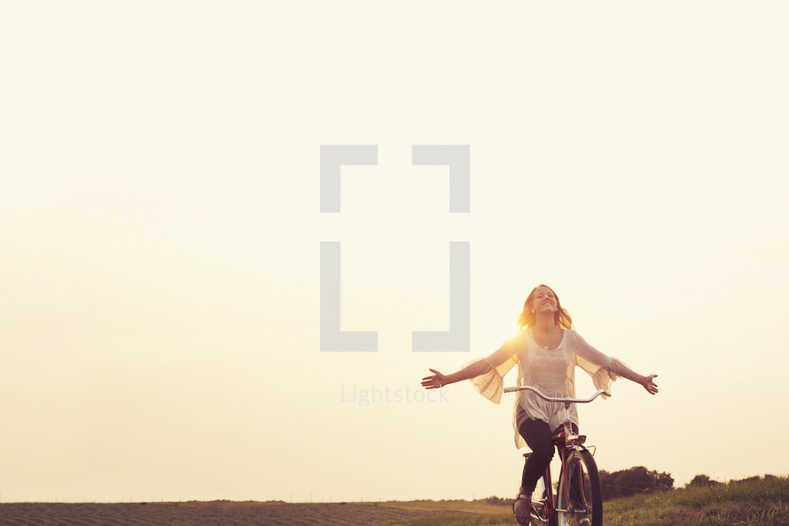 teenage girl riding a bicycle at sunset.