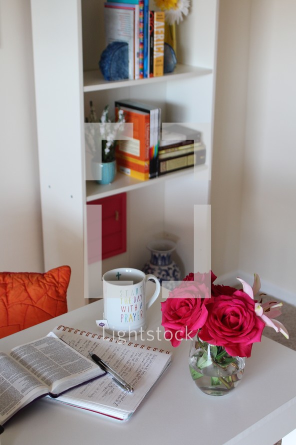 red roses in a vase and open Bible on a table 