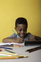 a boy child coloring on paper 