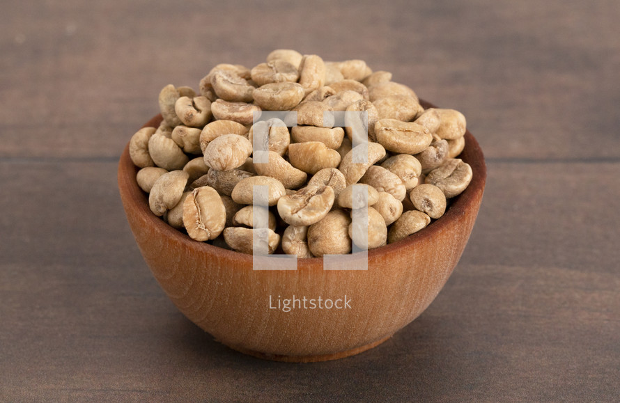 A Bowl of Raw Green Coffee Beans on a Wood Background