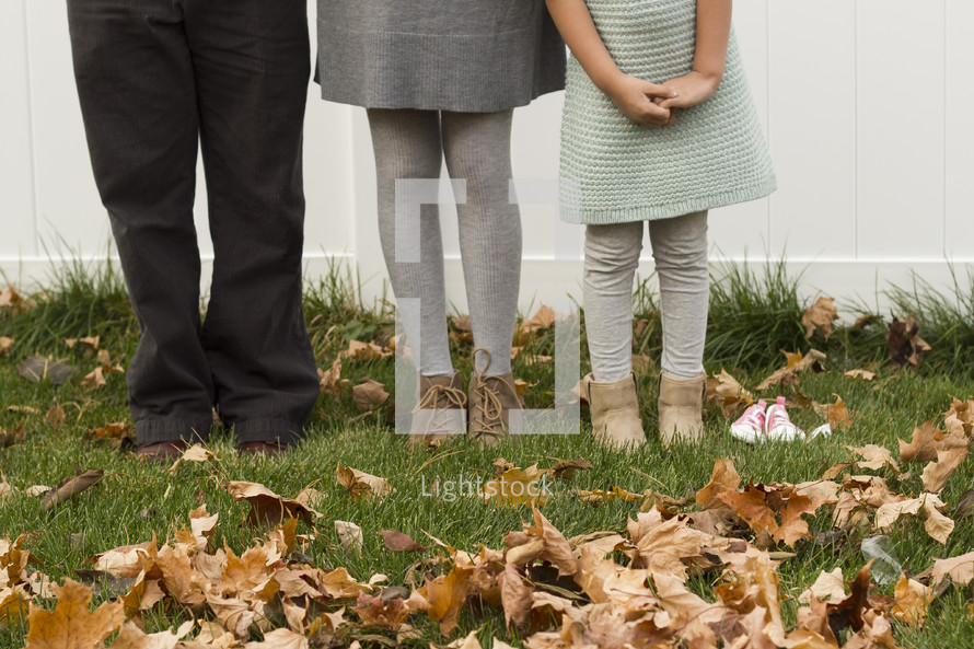 Family standing outside in fall leaves.
