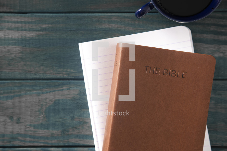 Bible, notebook, and coffee cup on a green wood background 