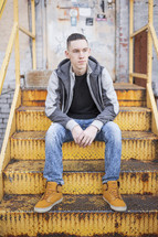 a young man sitting on rusty stairs 