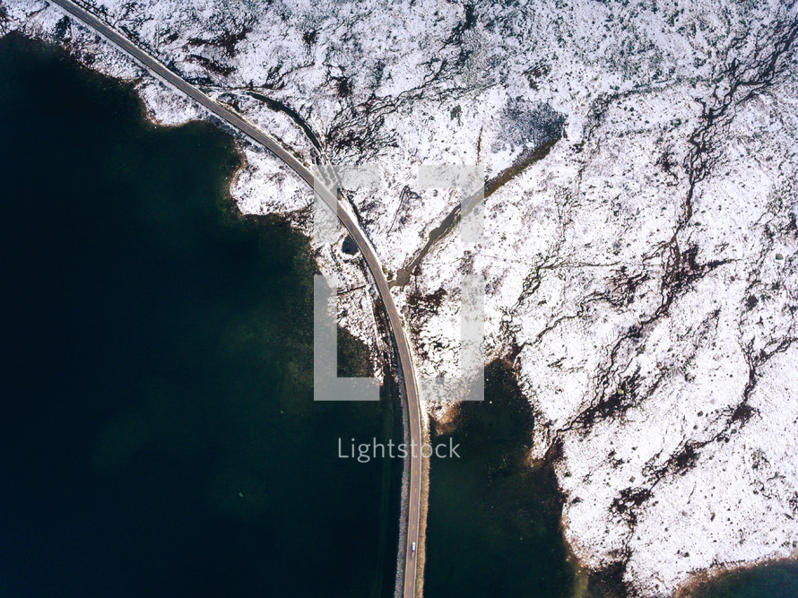 aerial view over highway hugging a shoreline 