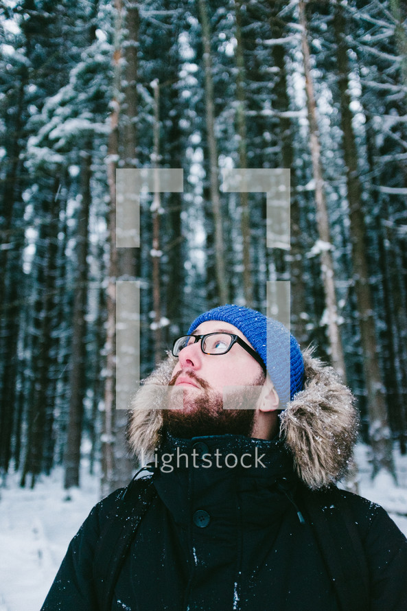 man looking up in a snowy forest 