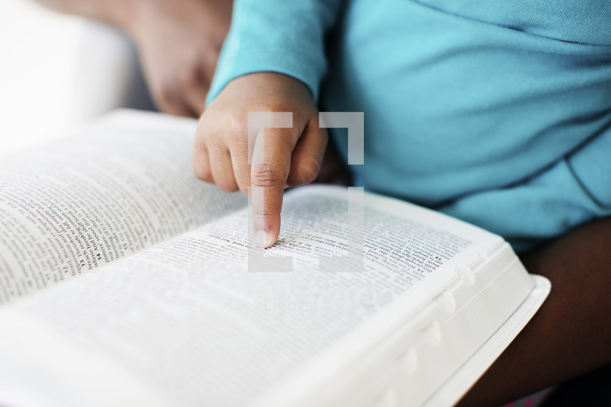 Little girl pointing to a verse in the Bible. 