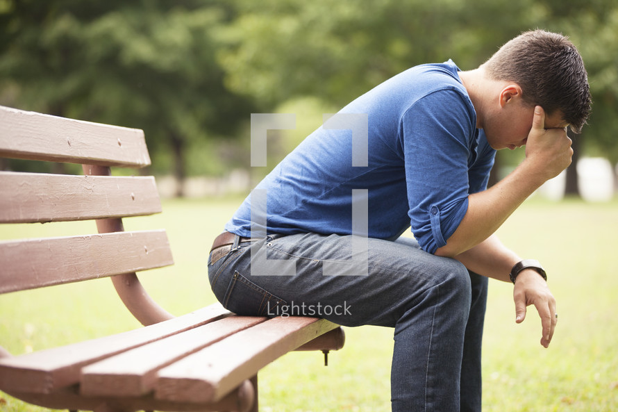 Worried man sitting on park bench.