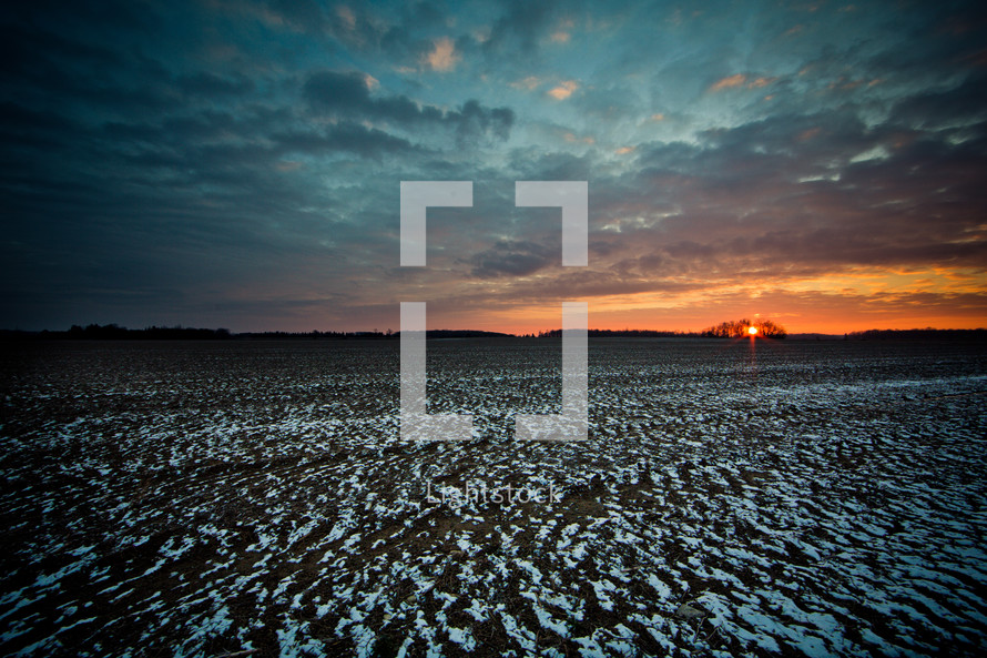 sunset over a snow dusted field