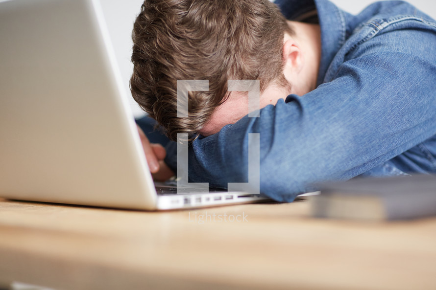 a person with his head on a his laptop computer keyboard 