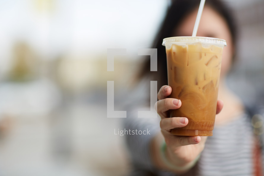 a woman holding an iced coffee 