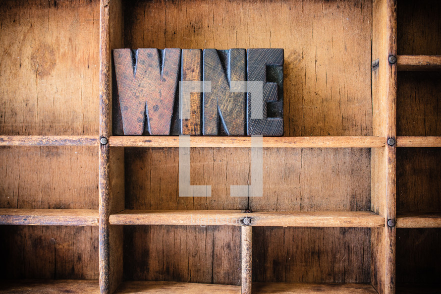 Wooden letters spelling "wine" on a wooden bookshelf.