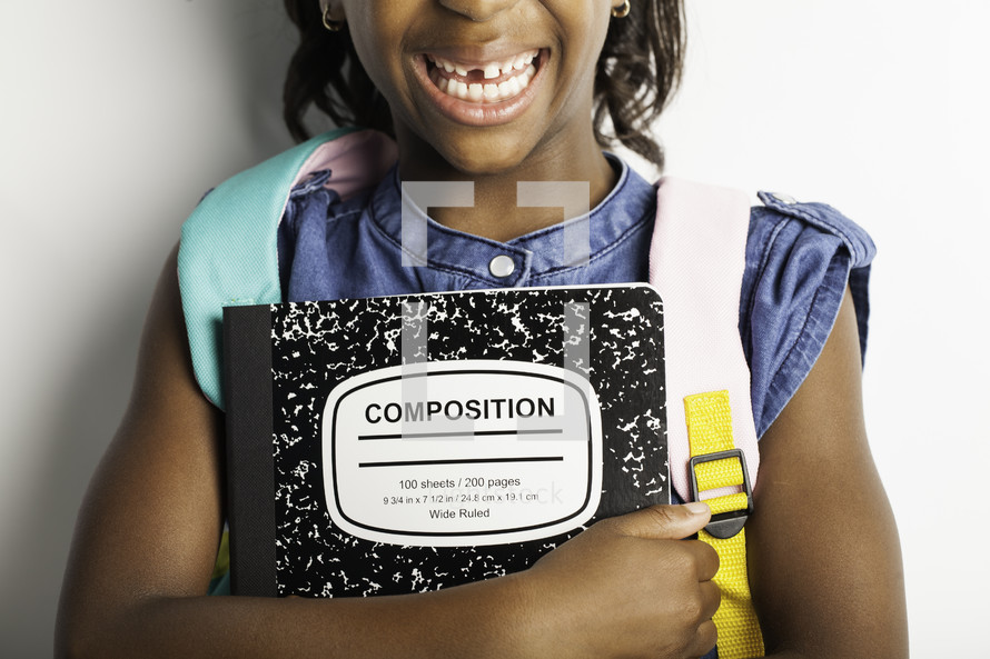 a girl child holding a composition notebook 