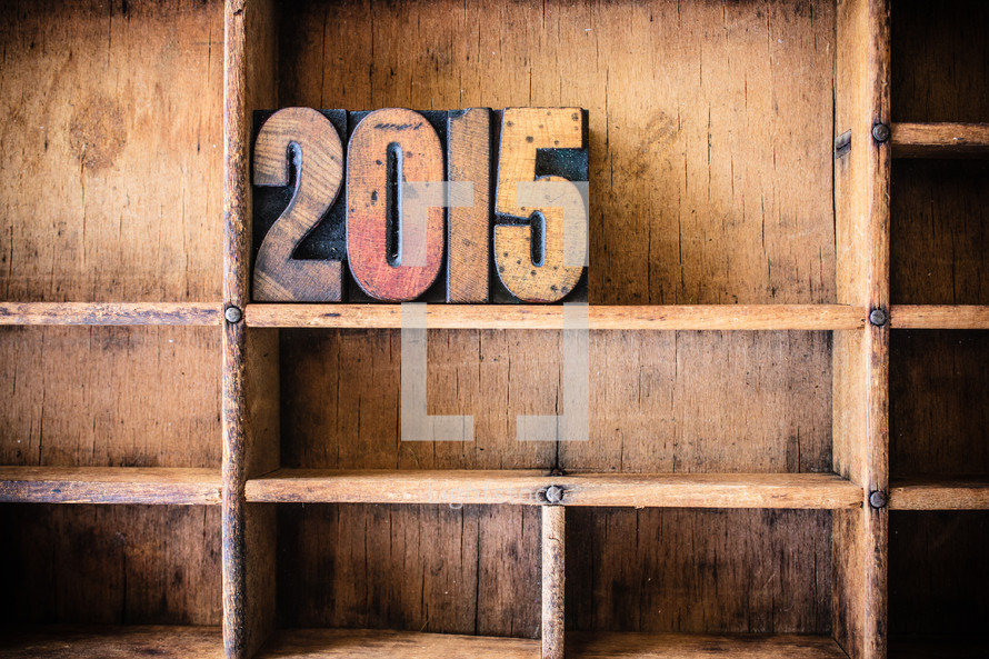Wooden letter spelling "2015" on a wooden bookshelf.