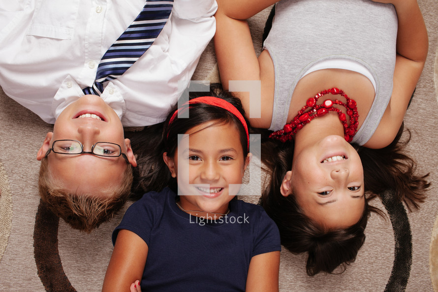 brothers and sisters lying on a rug 