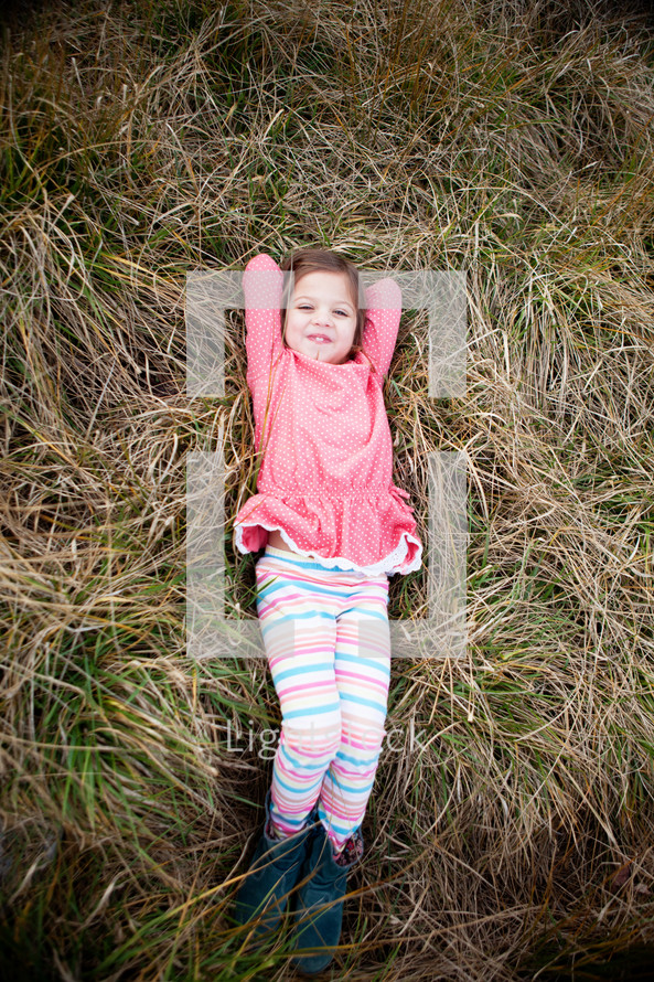 girl child lying in grass 