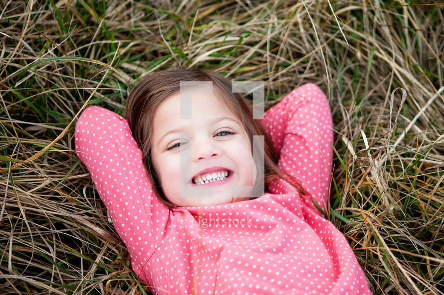 little girl lying in grass 