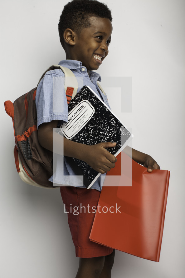 a boy child holding school supplies 