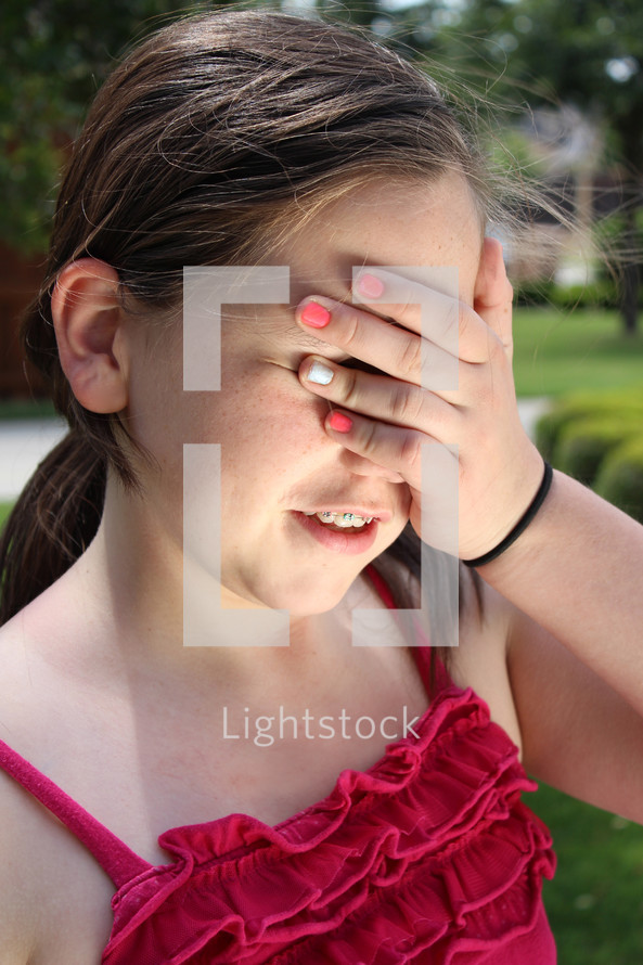teen girl covering her eyes with her hand 