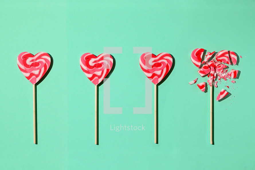 Red and white heart lollipops on a teal background