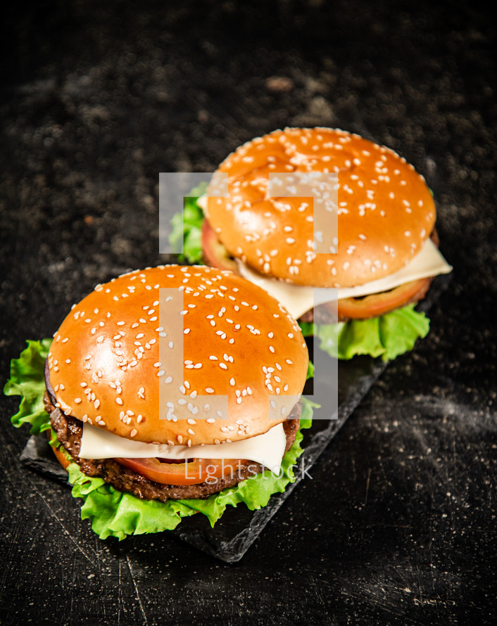 A burger on a stone board on a table. On a black background. High quality photo