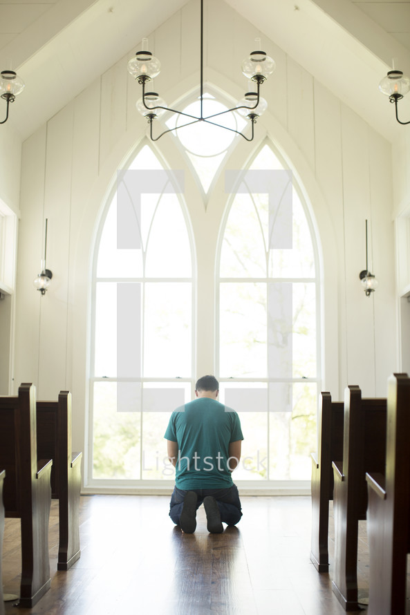 a man kneeling in prayer at church 